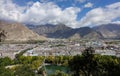 DRONE: Flying over a small green park and toward Lhasa and spectacular mountains Royalty Free Stock Photo