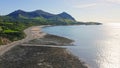 Drone flying over Trefor Beach and rugged Welsh coast in Wales with Yr Eifl Mountains in background