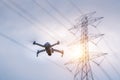 A drone is flying surveying equipment of high voltage pylons to inspect aerial view equipment on high voltage pylons. The concept