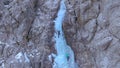 DRONE Flying towards a rocky wall as two ice climbers scale the frozen waterfall