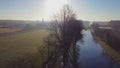 Drone flying up next to a river or canal and farm fields in Belgie around sunrise or sunset