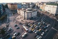 drone flyover of busy city center, with cars and people in the foreground