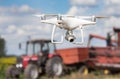 Drone in front of tractor and combine harvester in field Royalty Free Stock Photo