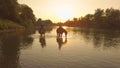 DRONE: Sunset illuminates active girls leading their horses down the river. Royalty Free Stock Photo