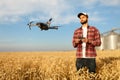 Drone hovers in front of farmer with remote controller in hands near grain elevator. Quadcopter flies near pilot Royalty Free Stock Photo