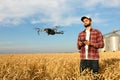 Drone hovers in front of farmer with remote controller in hands near grain elevator. Quadcopter flies near pilot Royalty Free Stock Photo