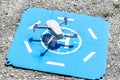 The drone hovers over the blue landing pad on the rocks, the plastic propellers are on, a visible USB slot and a memory card.