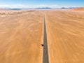 Drone image of offroad vehicle driving on barren and dry desert road in Sossusvlei, Namibia, with high orange sand dunes Royalty Free Stock Photo