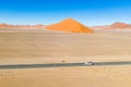 Drone image of offroad vehicle driving on desert road in Sossusvlei, Namibia with high orange sand dunes Royalty Free Stock Photo