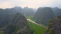 DRONE: Large murky river flowing past the rice paddies and spectacular cliffs. Royalty Free Stock Photo