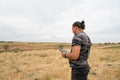Drone operator flying a drone in a dry field Royalty Free Stock Photo