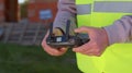 Drone operator holding remote controller controls an aircraft in front of construction house site