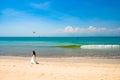 Drone over kissing bride and groom on beautiful beach, Bali. Asian couple in front of bright green sea and blue sky.