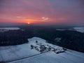 Drone panorama of amazing red sunrise behind clouds over bavarian forest and isolated farm area with snow in winter Royalty Free Stock Photo