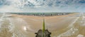 Drone panorama over the beach of the Belgian coastal town of Middelkerke at low tide with breakwaters during the day