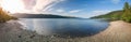 Drone panorama of Loch Ness captures sunlight casting a soft glow over the serene lake, pebbled beaches Royalty Free Stock Photo
