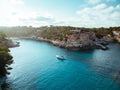 Drone panoramic image moored yachts on bright blue bay Cala Blanca Andratx, Palma de Mallorca, rocky coast breathtaking