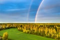 Drone photo, rainbow over summer pine tree forest,green wheat field, very clear skies and clean rainbow colors. Scandinavian Royalty Free Stock Photo