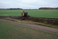 Drone photography of excavator cleaning drainage ditch in an agriculture field during autumn morning