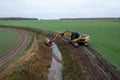Drone photography of excavator cleaning drainage ditch in an agriculture field during autumn morning