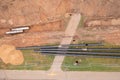 Drone photography of sewage pipe being lade down i a ditch by a road during autumn day