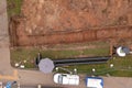 Drone photography of sewage pipe being lade down i a ditch by a road during autumn day