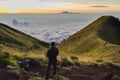 A drone pilot is flying quadrocopter on the mountain above the clouds. Sunrise at mount Merbabu, Indonesia, above the clouds.