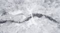Drone point of view of frozen river among snow. Beautiful snowy landscape with frozen stream.