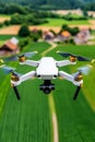A drone is in the process of refueling at a compact station, surrounded by vast open fields and distant farm buildings Royalty Free Stock Photo