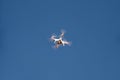 Drone quad copter fly on blue sky in background. Modern drone is flying in air, to take photos and record footage from above. Royalty Free Stock Photo