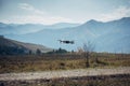 Drone quadcopter UAV with digital camera flying on the background with mountain, blue sky and white clouds. Professional drone Royalty Free Stock Photo