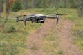 A drone quadrocopter with a camera with an ND filter hovers above the ground in flight and watches the road in the forest. Royalty Free Stock Photo