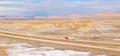 DRONE: Red semi-trailer truck hauls a heavy container across the snowy desert.