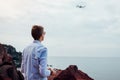 Drone remote control. Man operating copter controller by sea. Aerial video shooting of Red beach on Santorini island Royalty Free Stock Photo