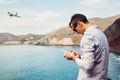 Drone remote control. Man operating copter controller by sea. Aerial video shooting of Red beach on Santorini island Royalty Free Stock Photo