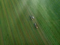 Drone shot of agricultural field with tractors harvesting hay