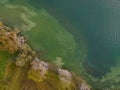 Drone shot. Birds view of clear lake with trees and buildings