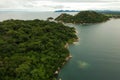 Drone shot of a coastline with green forest and mountains