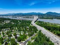 Drone shot of Coquitlam cityscape with Port Mann Bridge and river under blue sky