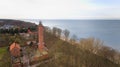 A drone captures Gaski beach, West Pomeranian Voivodeship, Poland, featuring a red brick lighthouse, Baltic Sea, sandy shore,