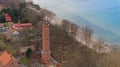 A drone captures Gaski beach, West Pomeranian Voivodeship, Poland, featuring a red brick lighthouse, Baltic Sea, sandy shore,