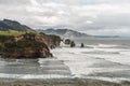 Drone shot of foamy waves of a sea crashing the huge rocks in it under the cloudy sky Royalty Free Stock Photo