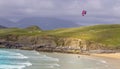 Drone shot of a kitesurfer on the shore under the cloudy sky