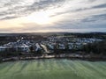 Drone shot of residential buildings and houses in a town near a green field under the cloudy sky Royalty Free Stock Photo