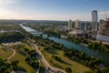 Drone shot of TX skyline with waterfront, greenery and blue cloudy sky in Austin city