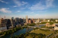 Drone shot of TX skyline with waterfront, greenery and blue cloudy sky in Austin city