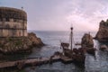 Drone shot of a wooden pier and old ships on the sea of a rocky coast near an ancient fortress Royalty Free Stock Photo