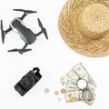 Drone, straw hat, camera, compass and coins with banknotes on white background. Flat lay, top view. Travel concept. Royalty Free Stock Photo