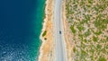 TOP DOWN: Gray car driving down the scenic coastal road on a sunny day in Lefkas Royalty Free Stock Photo