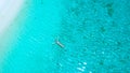 DRONE: Young woman on summer vacation floating on her back in the glassy ocean.